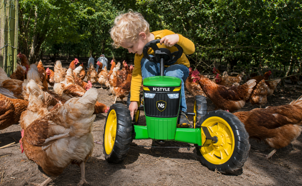 Toddler on tractor surrounded by chickens